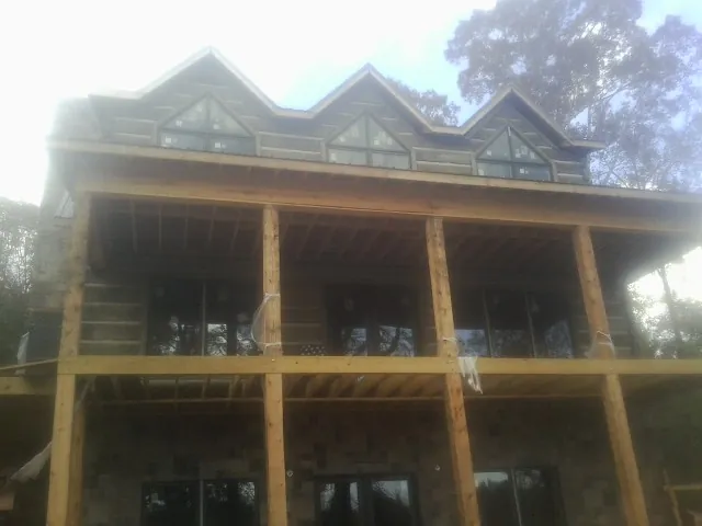 Dormers and porch framing on a large log home under construction — Roof Coating work by our crew in Kitzmiller