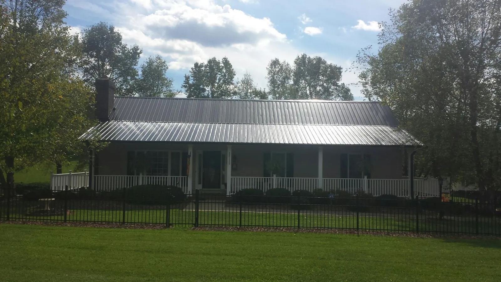 Gray metal roof on a brick ranch with a full width front porch — Gutter Guard Installation work by our crew in Kitzmiller