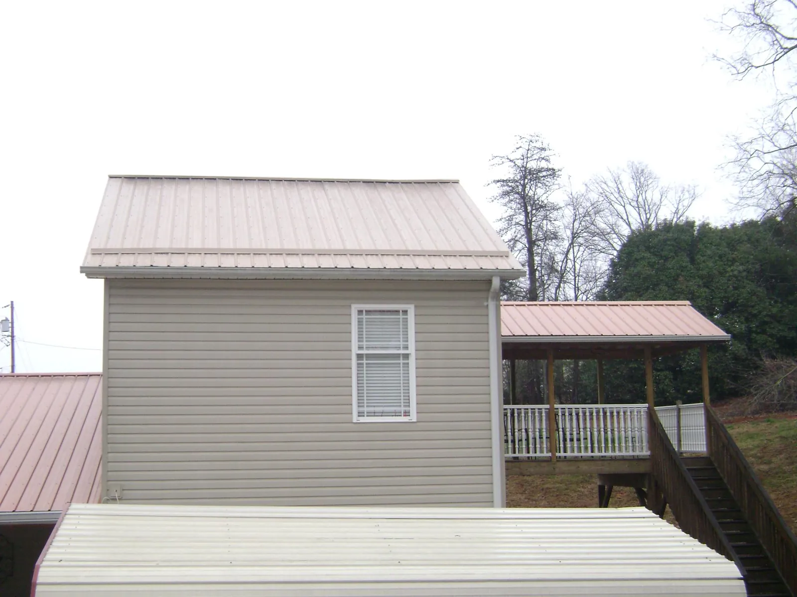 Tan metal roofs on a two story addition and attached porch, from a Roof Replacement job in Kitzmiller