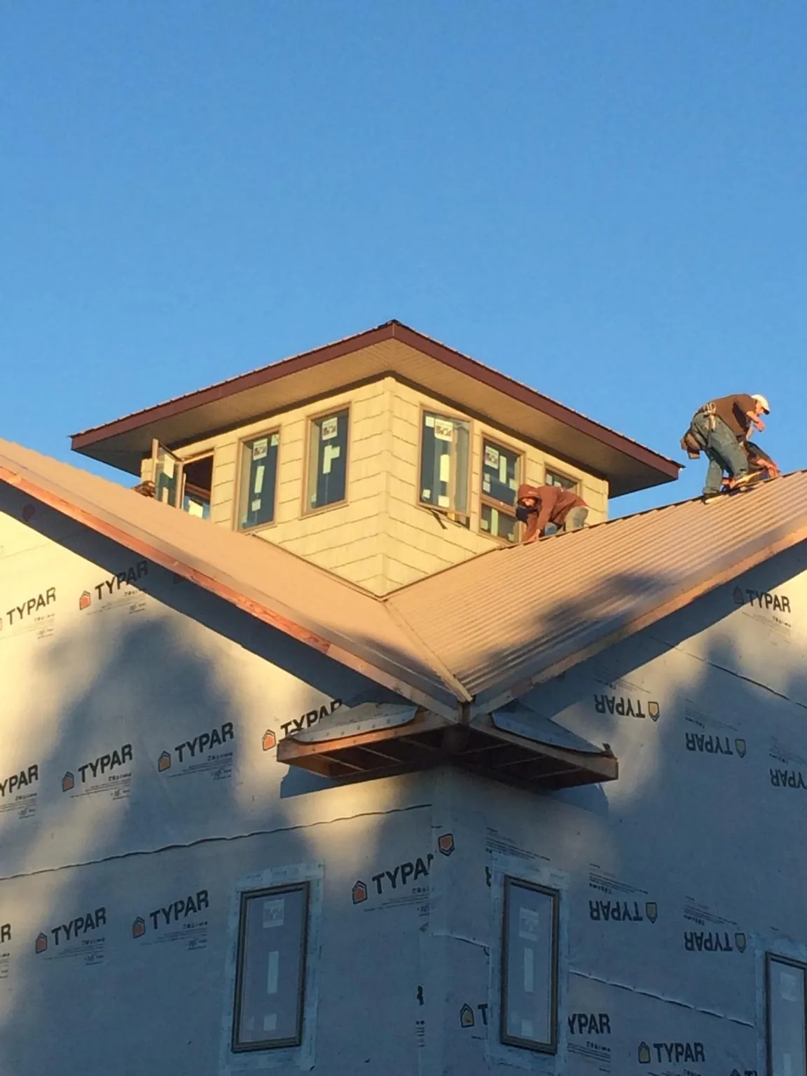 Roofers working around a rooftop cupola on a new metal roof at sunset — Roof Waterproofing in Kitzmiller by Roofing Brothers